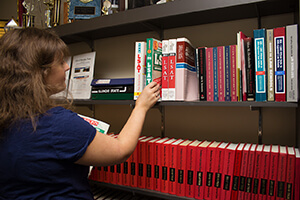Student picks out a book off a shelf.